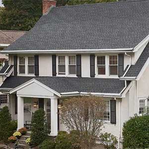 Front view of a typical mid-class home with two floors and gray GAF shingles on its roof
