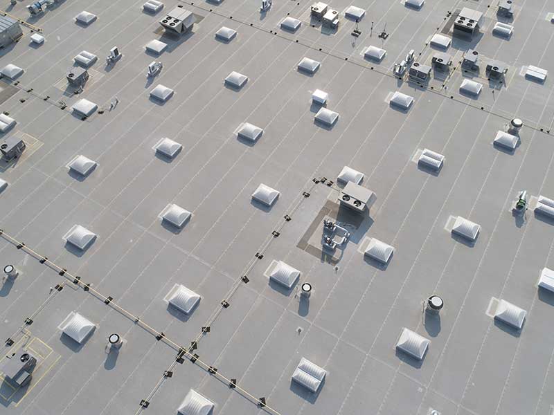 Top view of a commercial building with skylights and AC units scattered across it